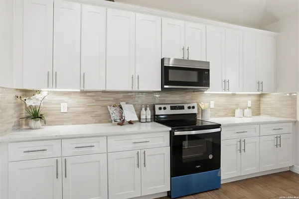a kitchen with granite countertop white cabinets and stainless steel appliances