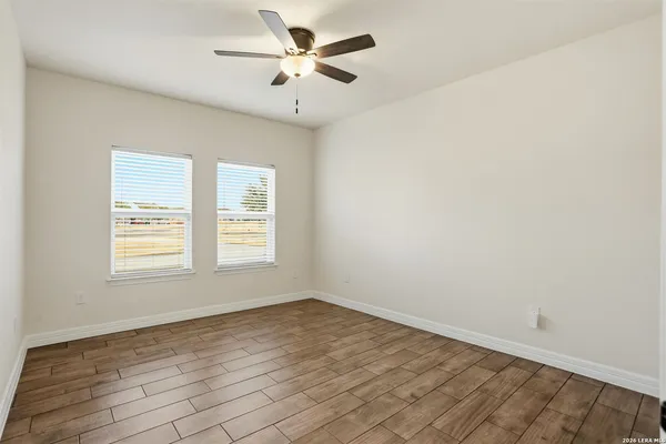 a view of empty room with wooden floor and ceiling fan