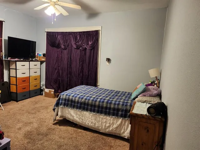 a bedroom with a bed and flat tv screen on the dresser