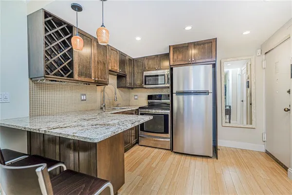 a kitchen with kitchen island a counter top space a sink stainless steel appliances and cabinets