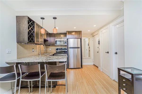 a kitchen with stainless steel appliances granite countertop a kitchen island hardwood floor and a sink