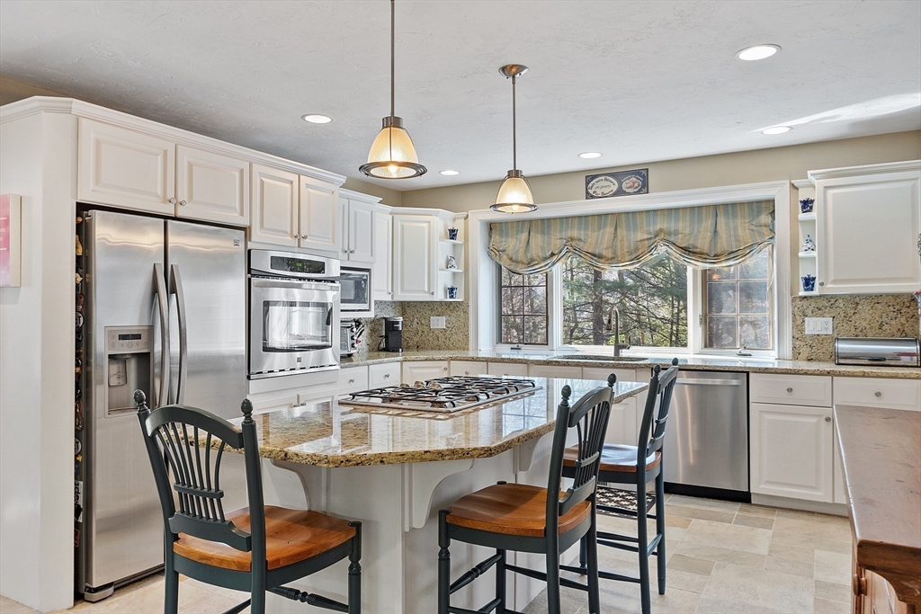 142 Pope Road Acton, MA 01720 - Photo 13 of 42 a kitchen with stainless steel appliances granite countertop a stove a refrigerator a kitchen island a table and chairs