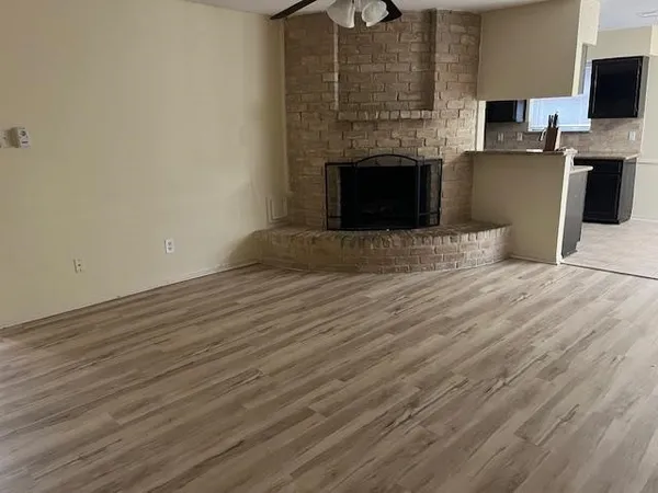 a view of empty room with wooden floor fireplace and flat screen tv