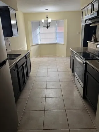 a kitchen with granite countertop a stove a sink and a counter top space
