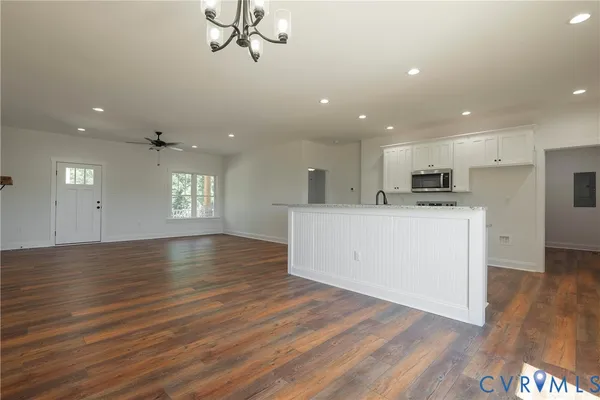 a view of an empty room and kitchen with wooden floor and window
