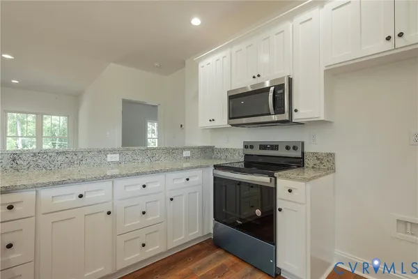 a kitchen with granite countertop white cabinets and a stove a oven with white countertops
