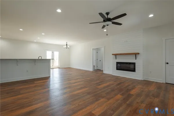 a view of an empty room with a ceiling fan kitchen view and a fireplace