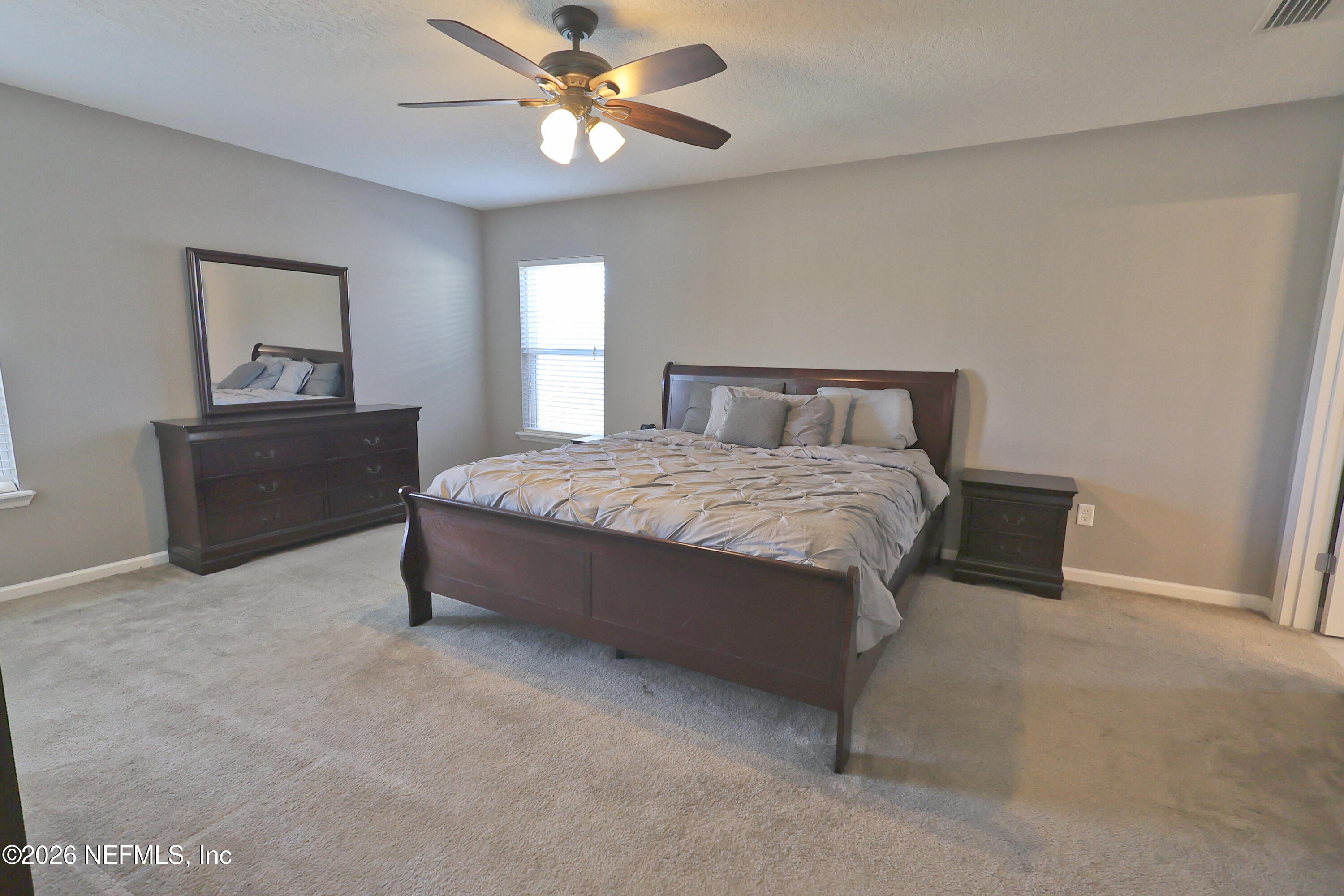 97569 Albatross Drive Yulee, FL 32097 - Photo 18 of 41 a spacious bedroom with a bed and a chandelier