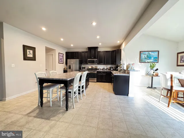 a kitchen with stainless steel appliances kitchen island granite countertop a table and chairs in it