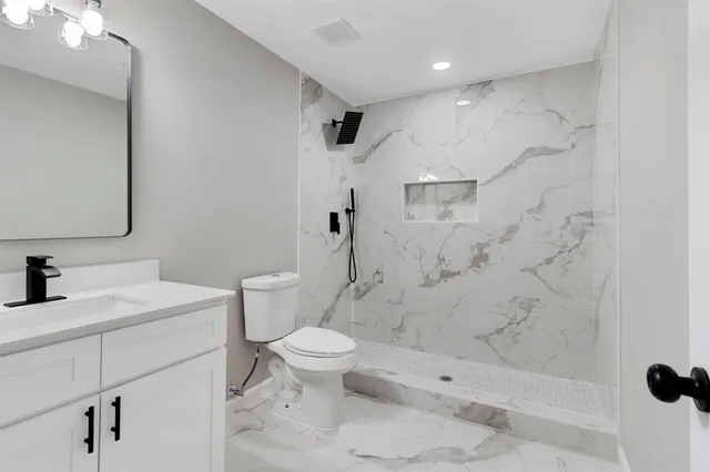a bathroom with a sink toilet vanity and shower