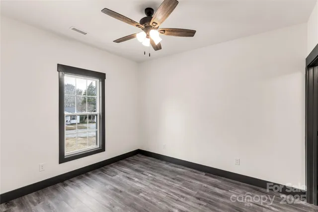 an empty room with wooden floor and a ceiling fan