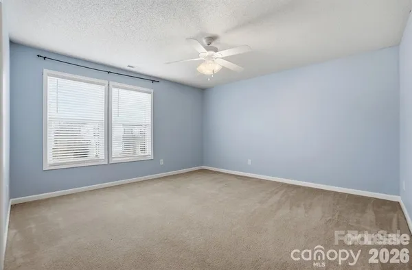 an empty room with windows and ceiling fan
