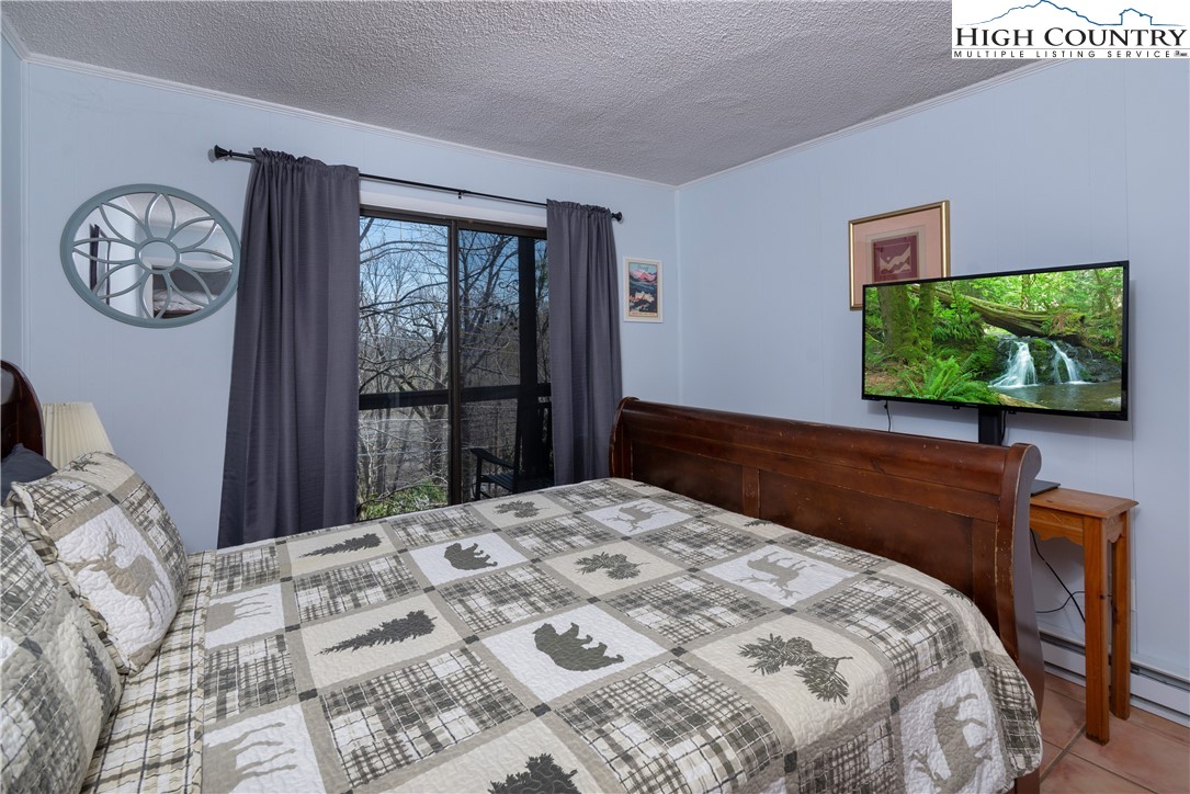 103 Mid Holiday Lane, Unit 115D Beech Mountain, NC 28604 - Photo 12 of 25 a bedroom with a bed and a flat tv screen on dresser