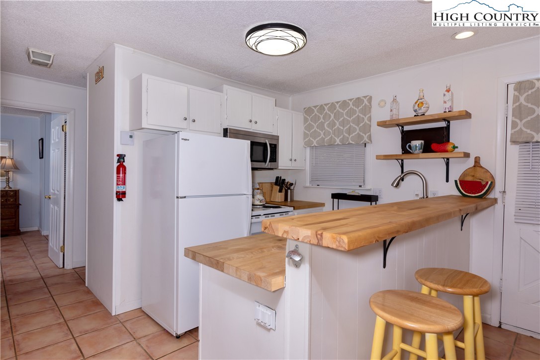 103 Mid Holiday Lane, Unit 115D Beech Mountain, NC 28604 - Photo 8 of 25 a kitchen with stainless steel appliances granite countertop a sink refrigerator and cabinets