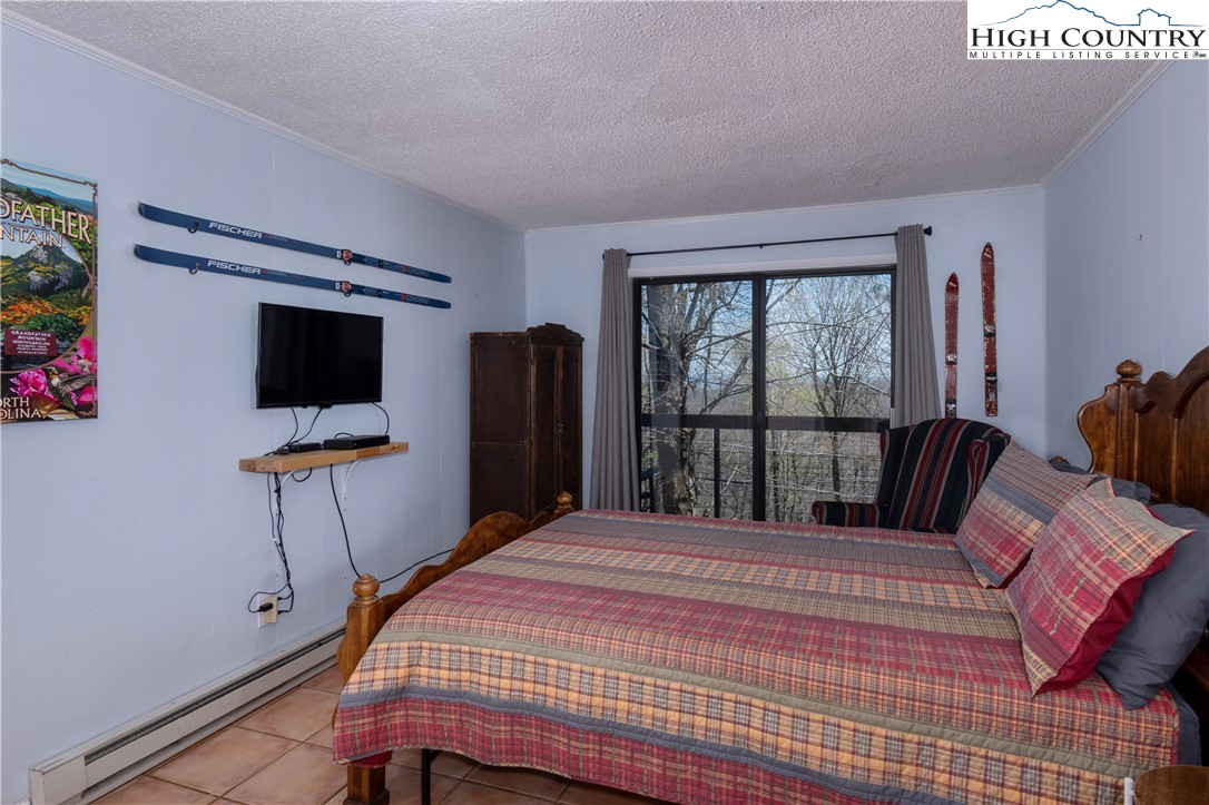 103 Mid Holiday Lane, Unit 115D Beech Mountain, NC 28604 - Photo 10 of 25 a bedroom with a bed tv and a large window