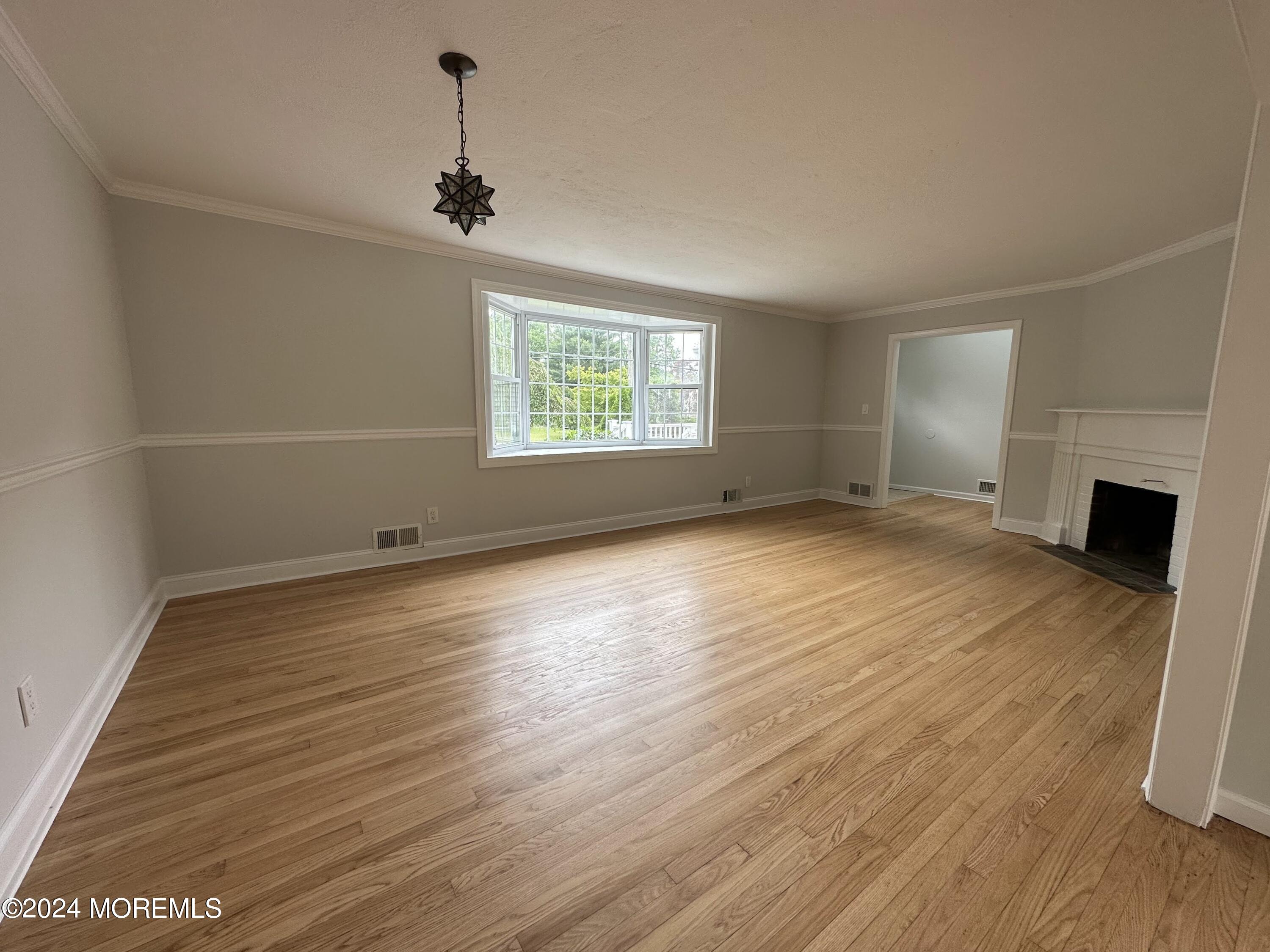 57 Kings Road Little Silver, NJ 07739 - Photo 5 of 22 an empty room with wooden floor fireplace and windows