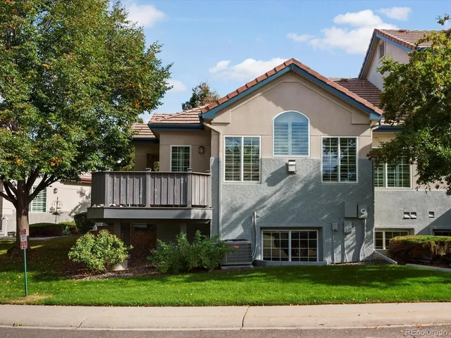 a view of a white house next to a yard with plants and large trees