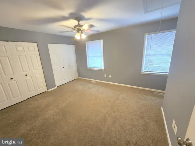 an empty room with chandelier fan and windows
