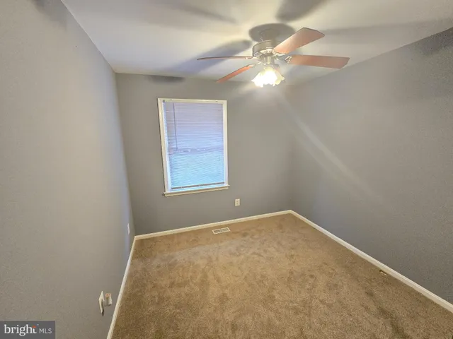 an empty room with a chandelier fan and windows