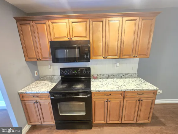 a kitchen with granite countertop a stove top oven microwave and cabinets