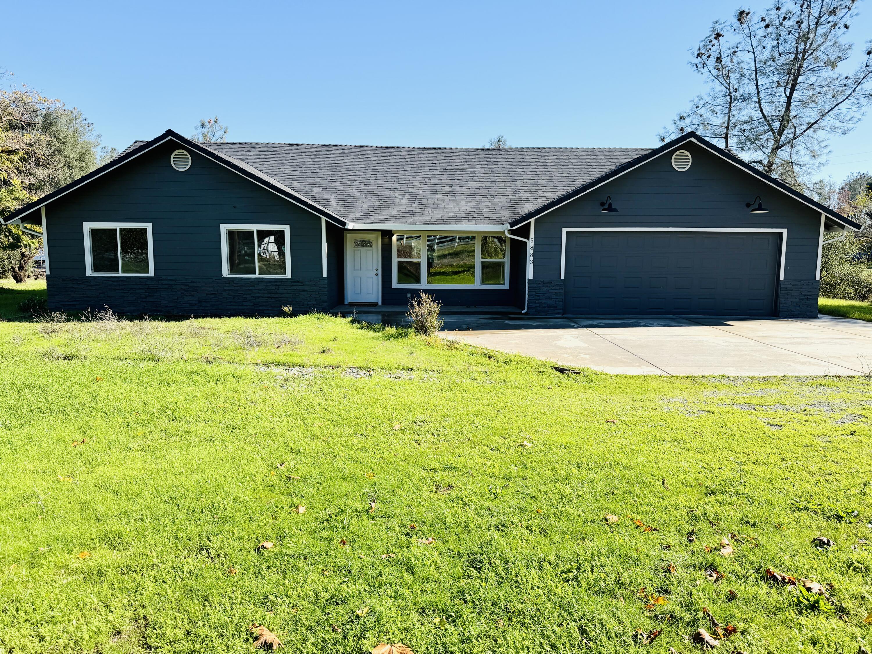 a front view of house with yard and trees in the background