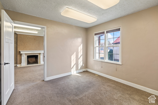 465 North Main Street Richfield, UT 84701 - Photo 30 of 43 Empty room with baseboards, a fireplace with flush hearth, a textured ceiling, and carpet flooring