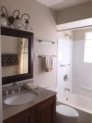 a bathroom with a granite countertop sink toilet and shower