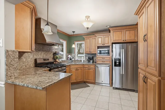 a kitchen with stainless steel appliances granite countertop a refrigerator a stove a sink and a microwave