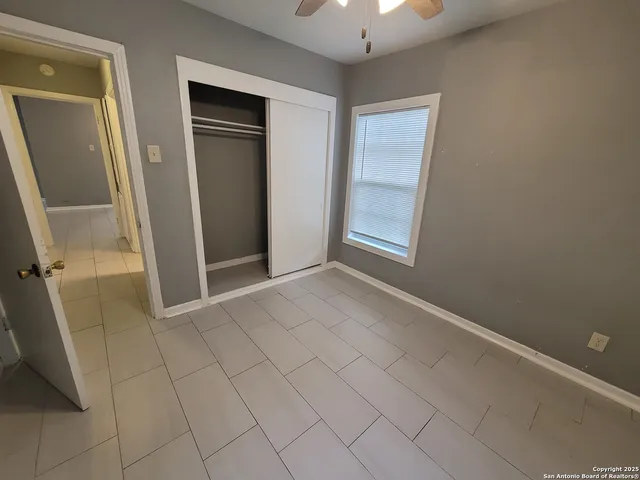 a view of an empty room with a chandelier fan