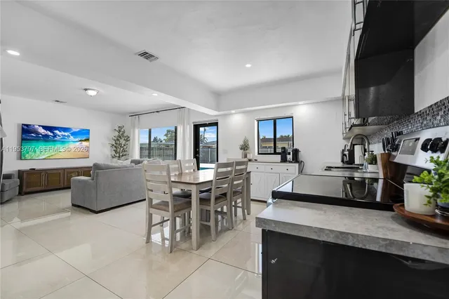 a living room with furniture a flat screen tv and kitchen view