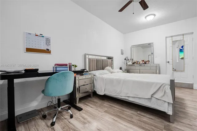 a bedroom with a bed a desk and chair with wooden floor