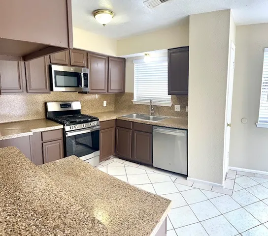 a kitchen with stainless steel appliances kitchen island granite countertop a sink stove and refrigerator