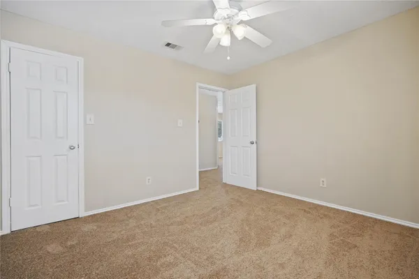 an empty room with a chandelier fan and closet area