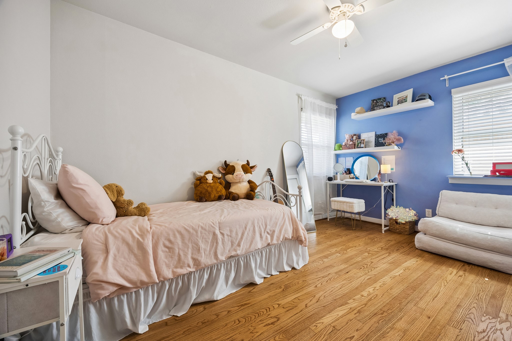 4514 Warm Springs Road Houston, TX 77035 - Photo 23 of 31 This beautiful bedroom features a cheerful periwinkle accent wall. It's well-lit with natural light from two windows, includes a ceiling fan and shelves for decor. The closet not pictured is to the right of the white chair.