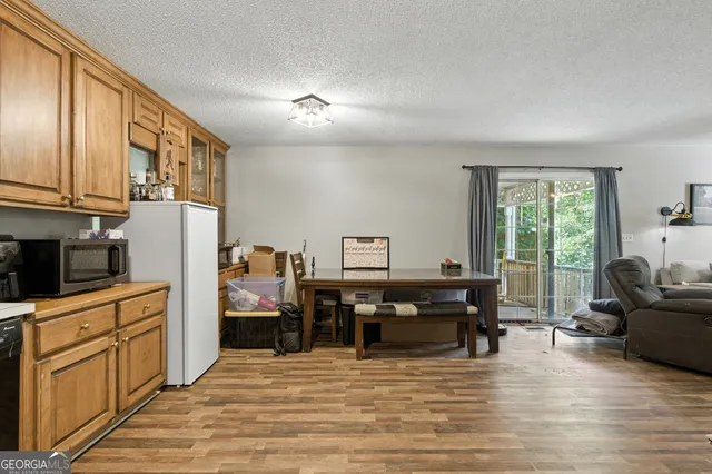 a view of a kitchen with kitchen island granite countertop a refrigerator a stove top oven a dining table and chairs with wooden floor