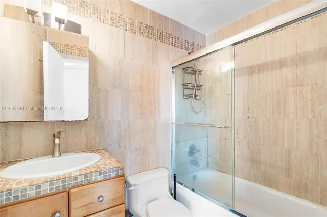 a bathroom with a granite countertop sink a toilet and shower