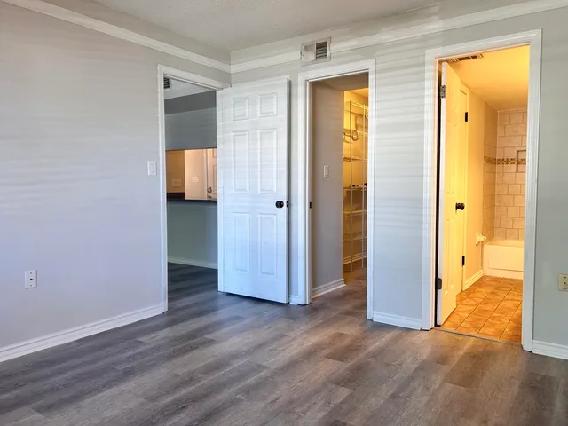 a view of a hallway with wooden floor and a bathroom