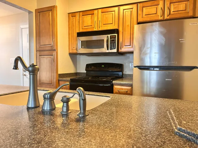 a kitchen with a refrigerator a stove and a sink with wooden floor