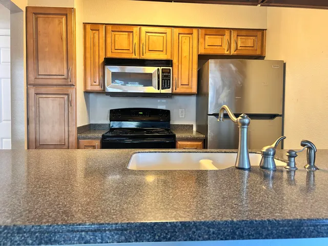 a kitchen with stainless steel appliances granite countertop a stove a microwave and a refrigerator