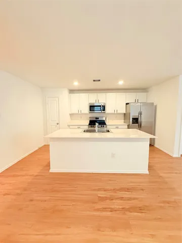 a view of kitchen with stainless steel appliances granite countertop a stove top oven a sink and white cabinets