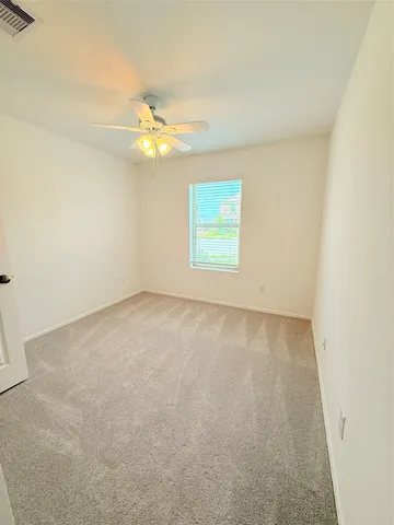 an empty room with a window and ceiling fan