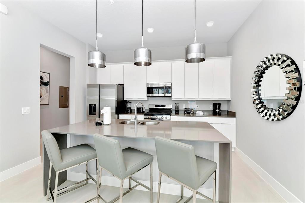 7770 Sandy Ridge Drive, Unit 135 Kissimmee, FL 34747 - Photo 17 of 43 a kitchen with stainless steel appliances kitchen island granite countertop a stove a sink a dining table and chairs with wooden floor