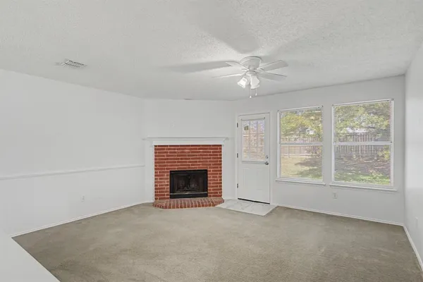 a view of empty room with fireplace ceiling fan and windows