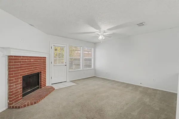 an empty room with windows fireplace and fan