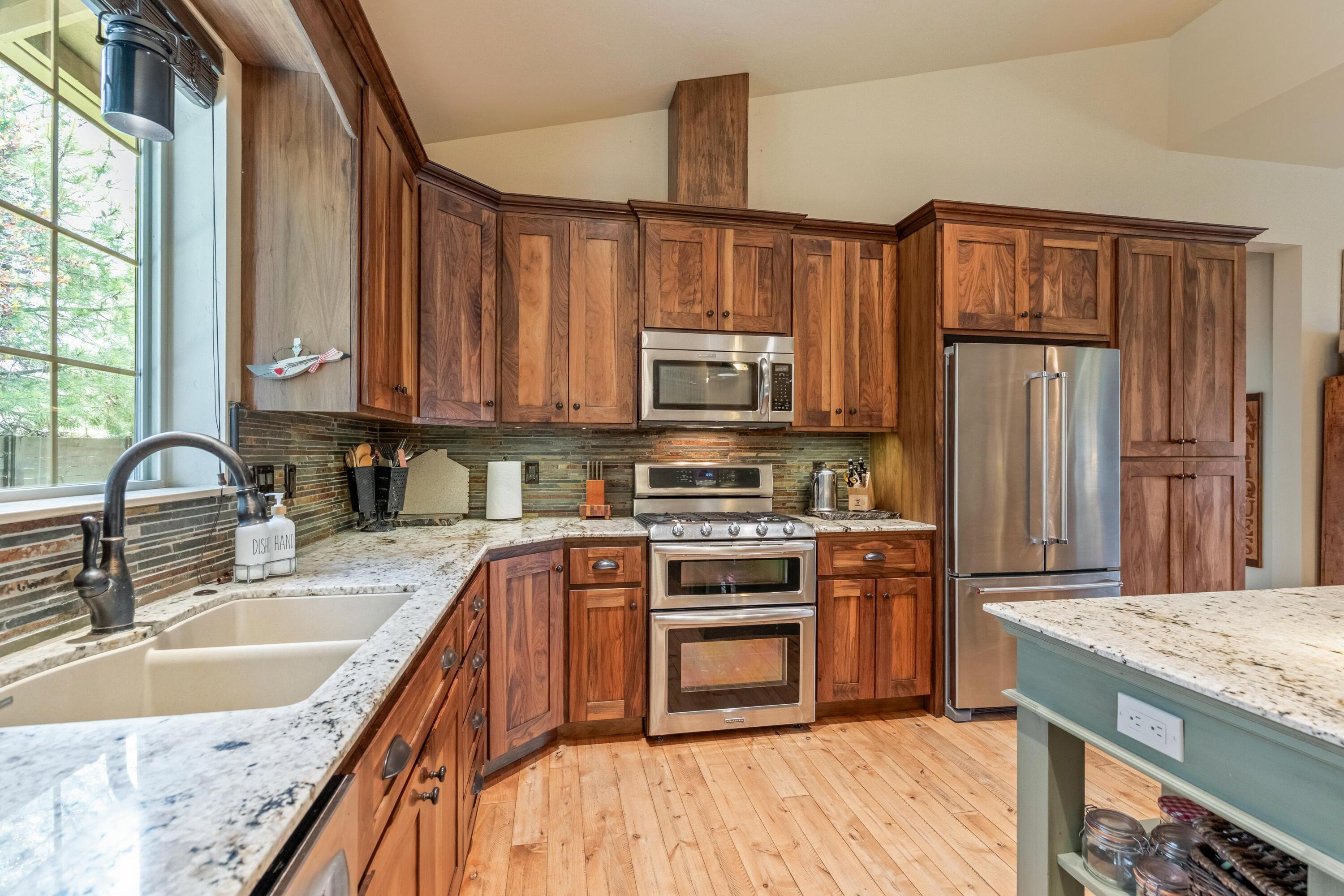 210 Northwest Saddle Ridge Loop Prineville, OR 97754 - Photo 9 of 38 a kitchen with stainless steel appliances granite countertop a stove top oven a refrigerator and a sink with wooden cabinets