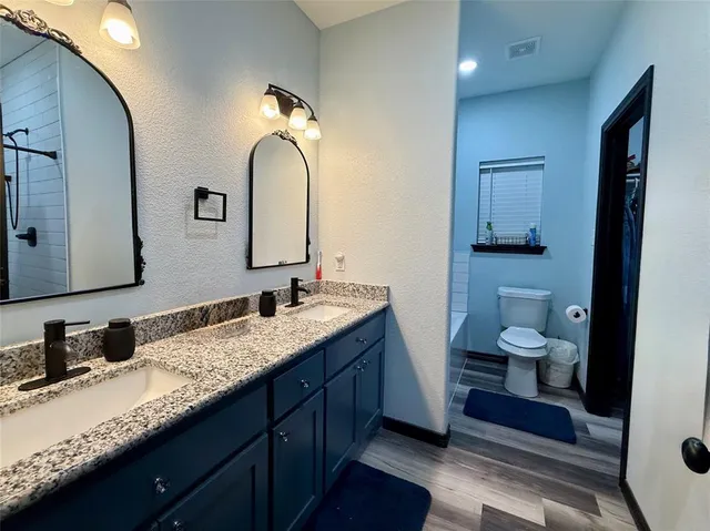 a bathroom with a granite countertop toilet sink and mirror