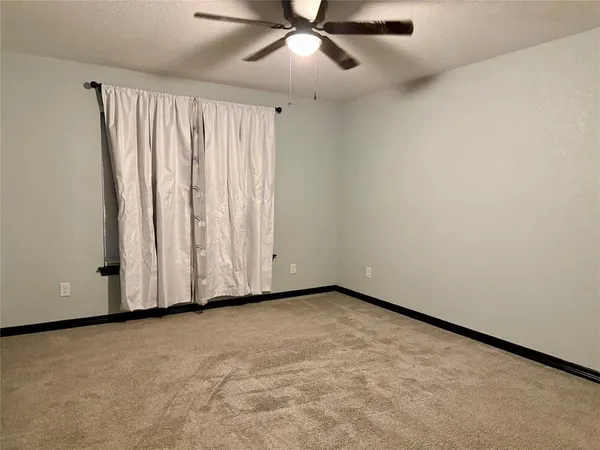 an empty room with a ceiling fan and a window