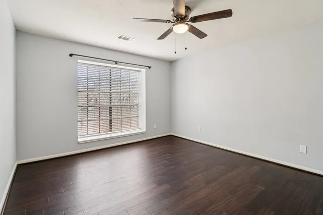 a view of an empty room with window and wooden floor