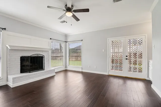a view of an empty room with wooden floor fireplace and a window