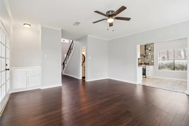 an empty room with wooden floor and ceiling fan
